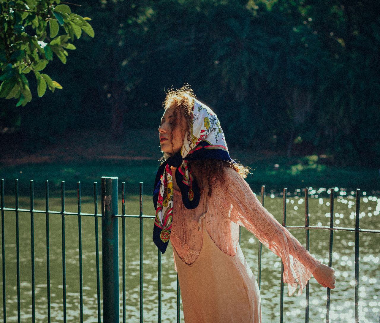 A woman with a headscarf enjoys a moment by a scenic lake in São Paulo.